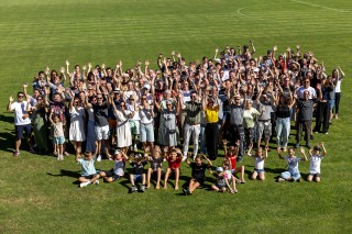 Gäste der Veranstaltung kamen auf dem Sportplatz für ein gemeinsames Gruppenfoto 
zusammen.